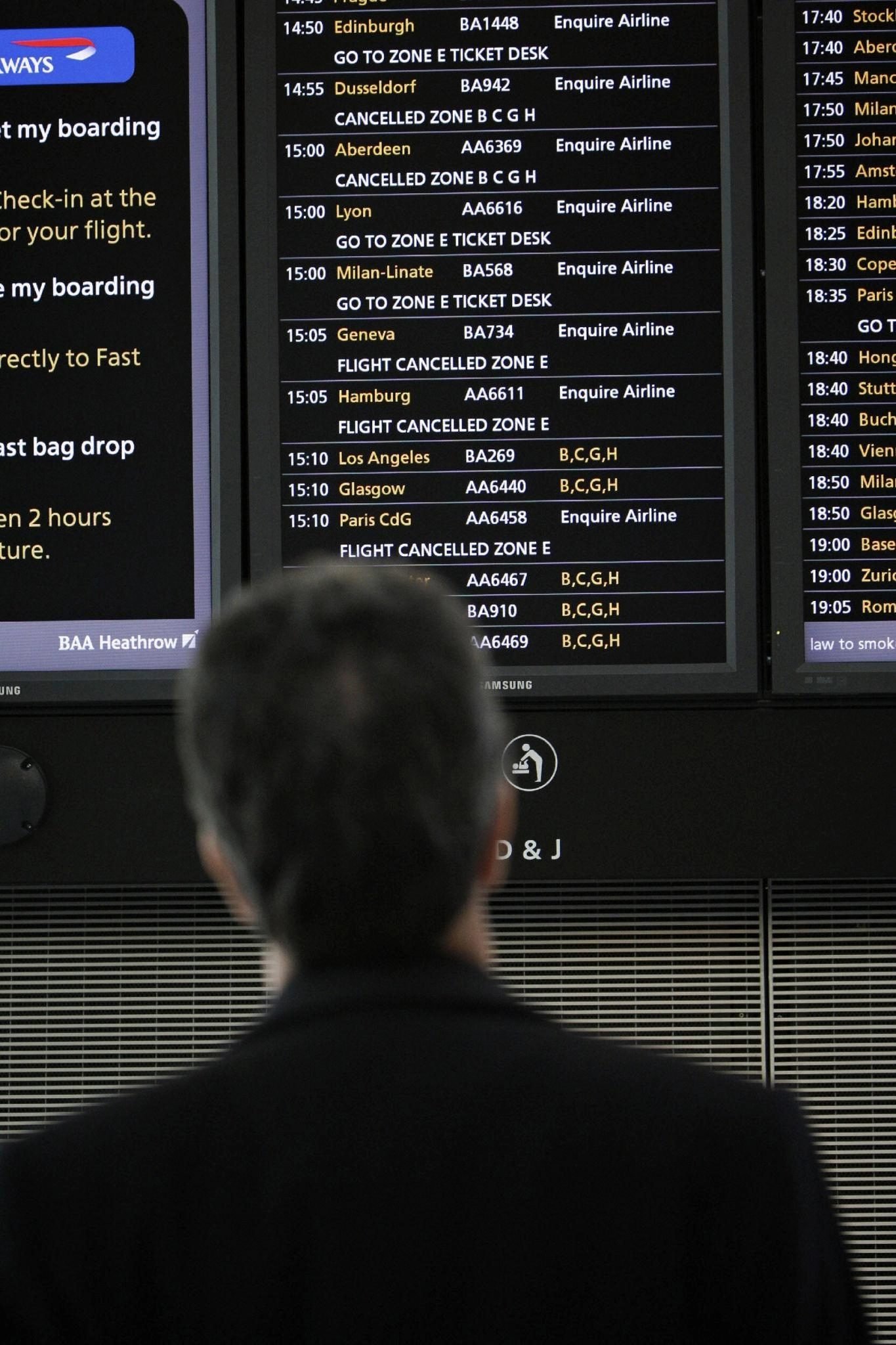 Passengers check cancelled and delayed flight information at London Heathrow Airport amid UK air traffic control disruption